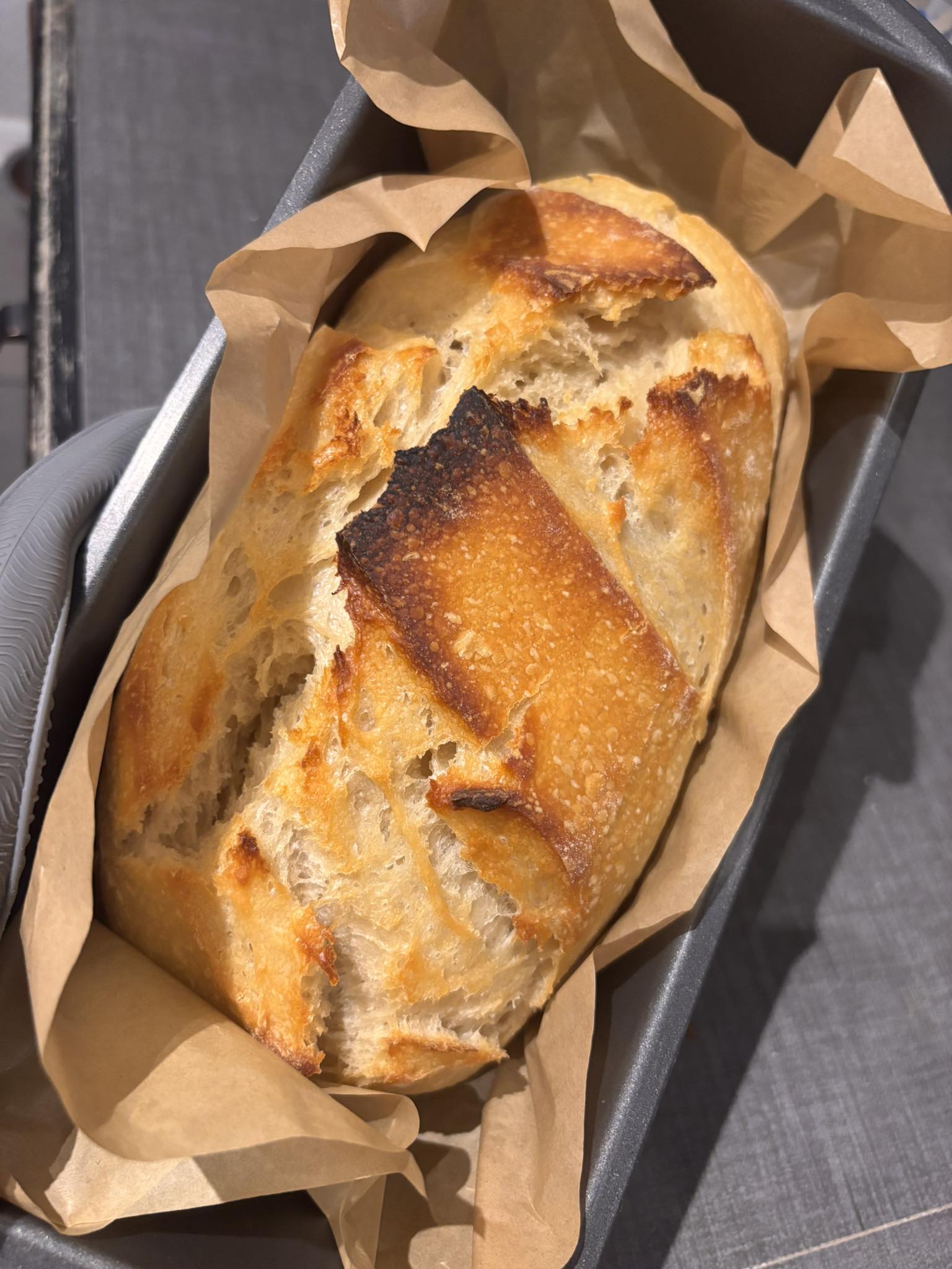 A single sourdough loaf in a parchment-lined pan