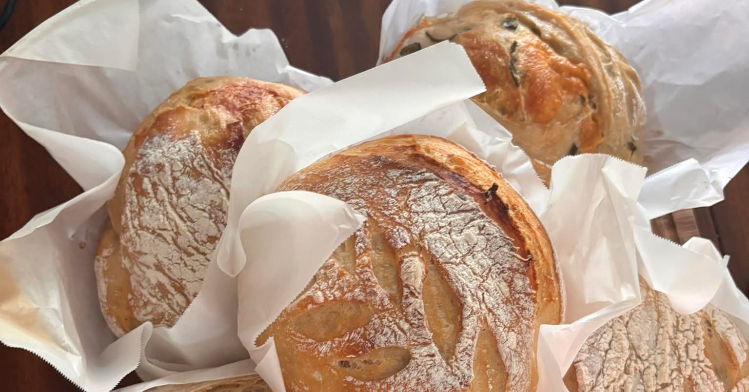 A basket of fresh-baked sourdough loaves wrapped in parchment paper